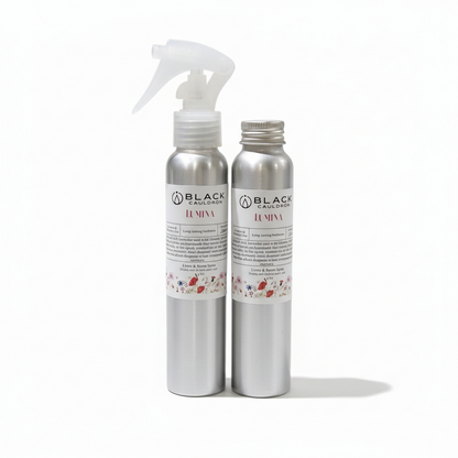 Two silver bottles with labels on a white background.   Lumina room and linen spray 