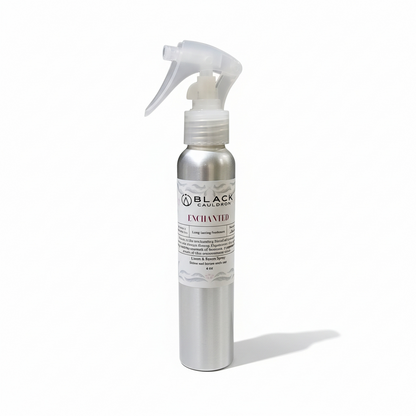 Silver spray bottle with a label on a white background.  Enchanted room and linen spray 